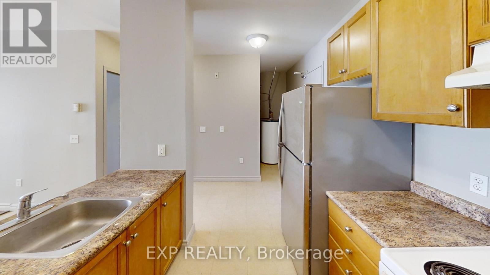 A kitchen with wooden cabinets and a stainless steel refrigerator.