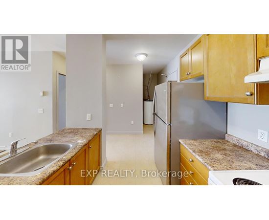 A kitchen with wooden cabinets and a stainless steel refrigerator.