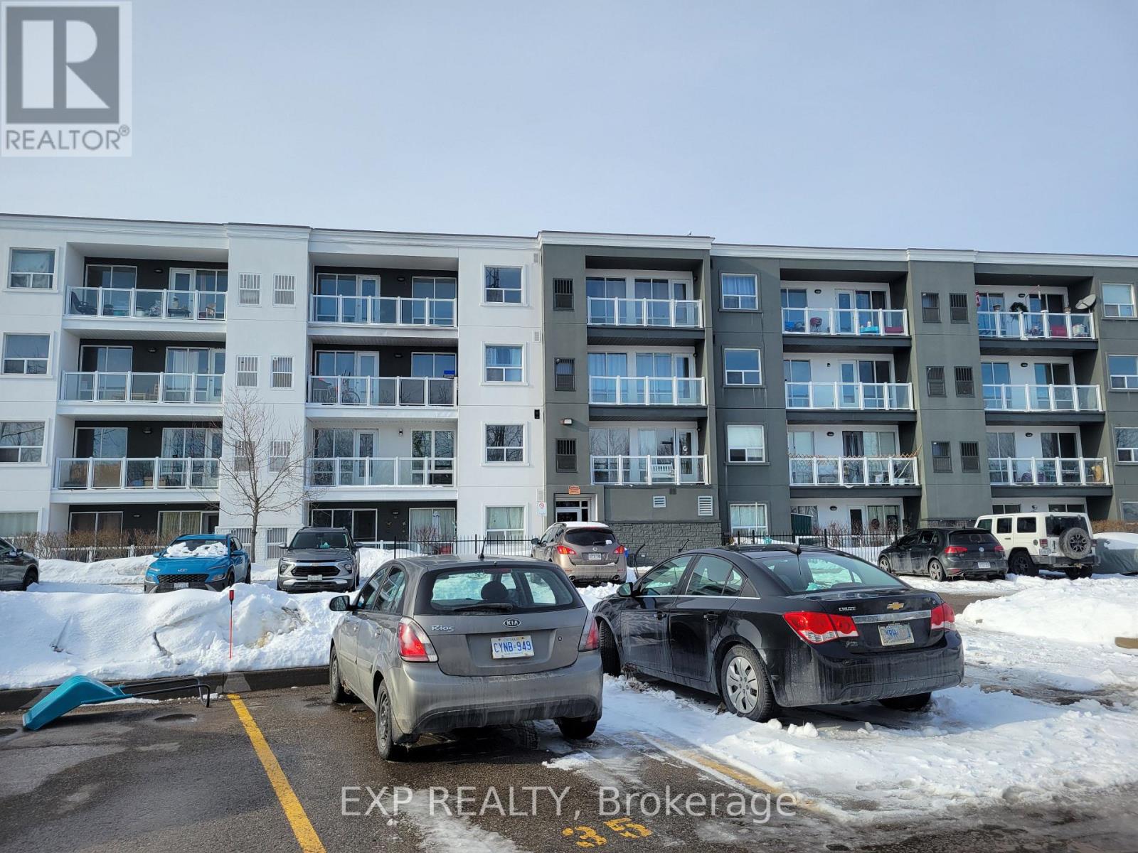 Cars parked in a lot in front of apartment buildings.