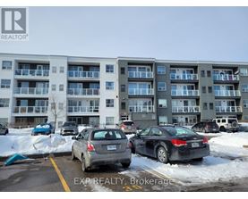 Cars parked in a lot in front of apartment buildings.