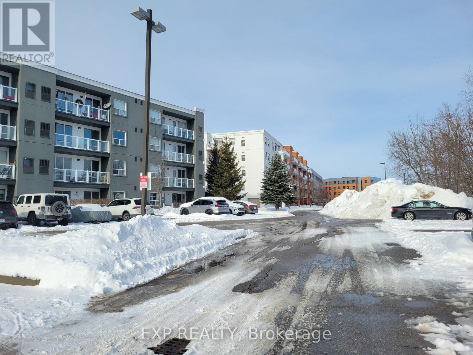 A snowy street with cars parked on the side.