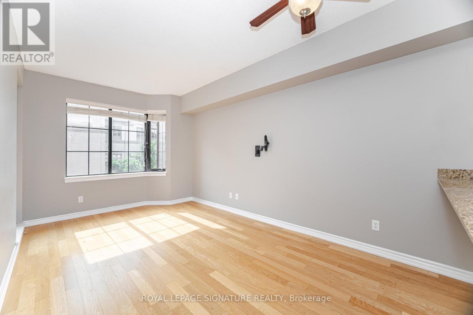 A spacious room with wooden flooring and a ceiling fan.
