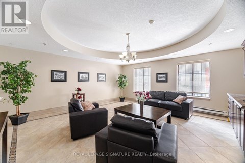 A living room with a black couch and a chandelier.