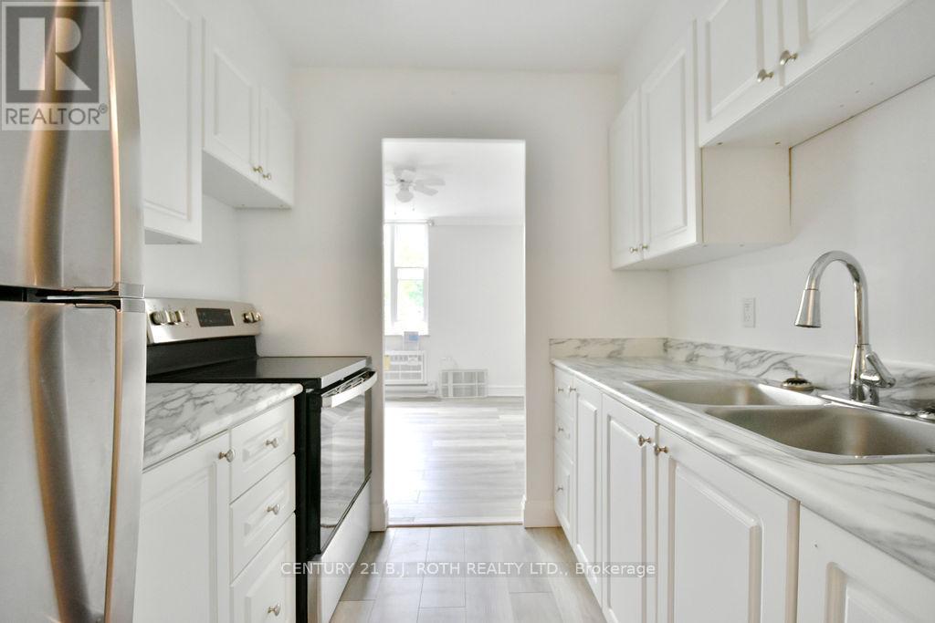 A kitchen with white cabinets and a marble countertop.