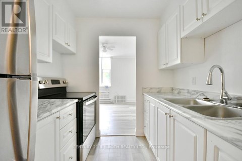 A kitchen with white cabinets and a marble countertop.