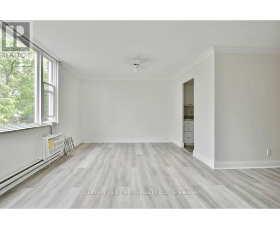 A spacious room with a window and a door leading to another room.