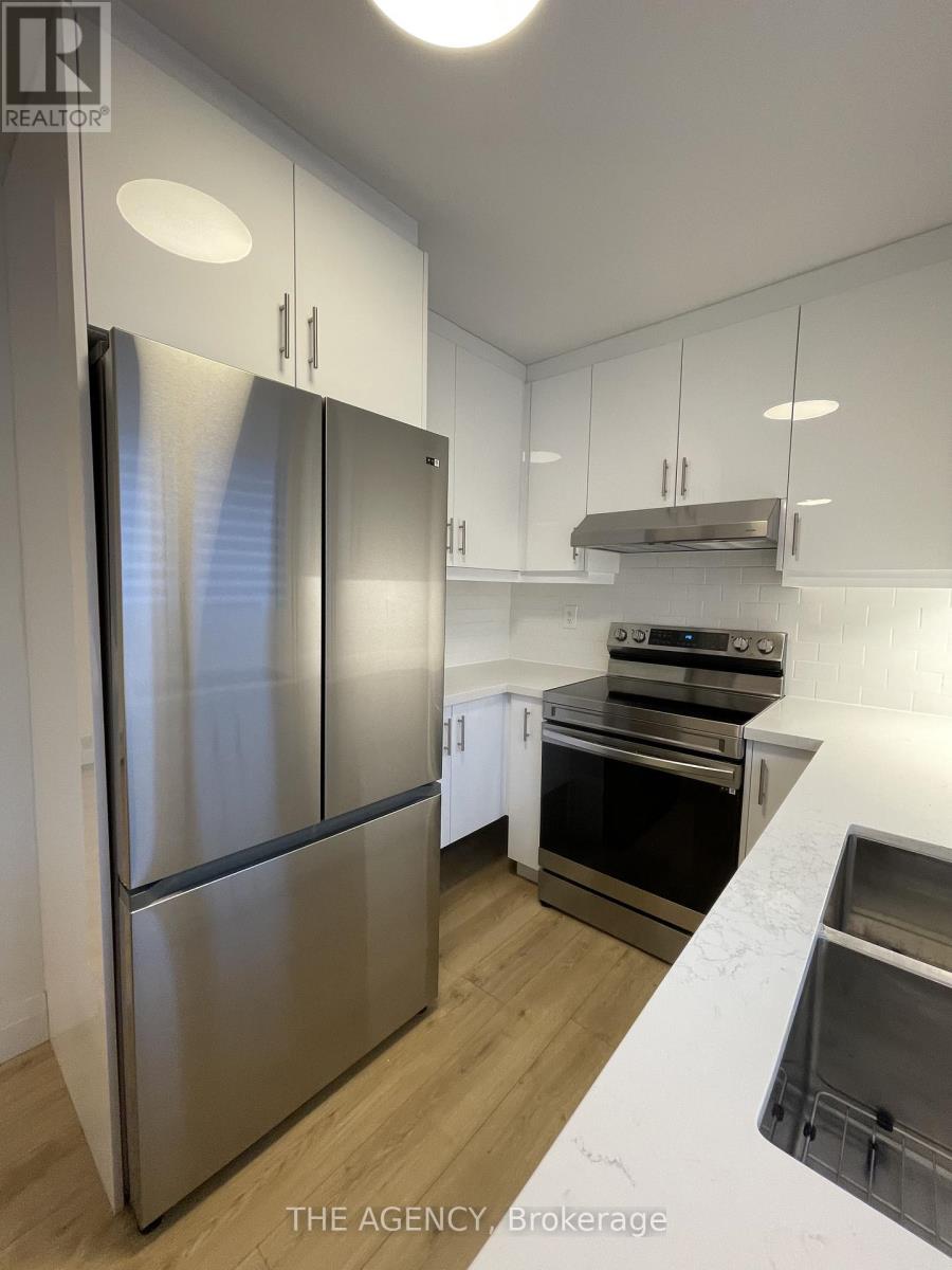 A modern kitchen with a stainless steel refrigerator and wooden flooring.