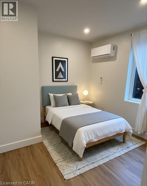 A bedroom with a bed, pillows, a nightstand, and a window.