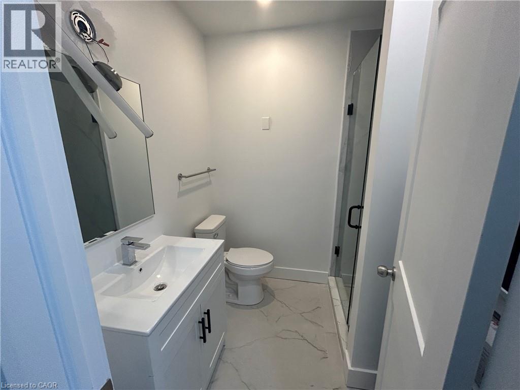 A bathroom with a toilet, sink, and mirror.
