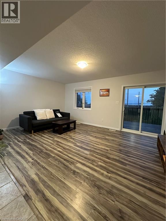 A living room with a black couch and wooden flooring.