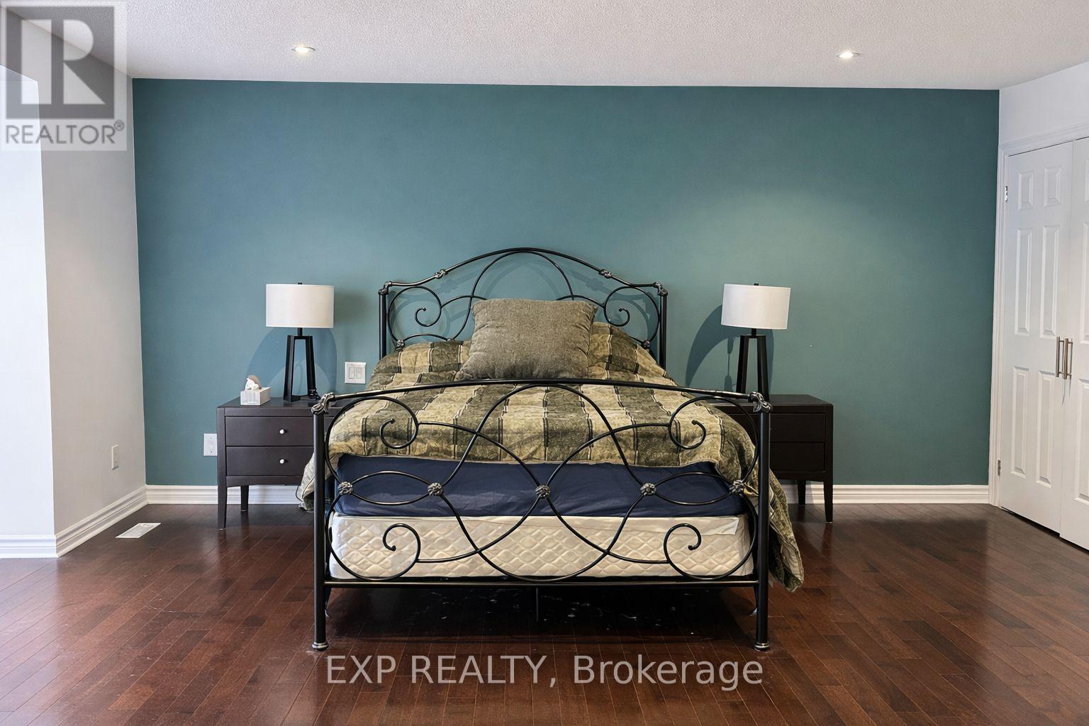 A bedroom with a bed, nightstands, and lamps.