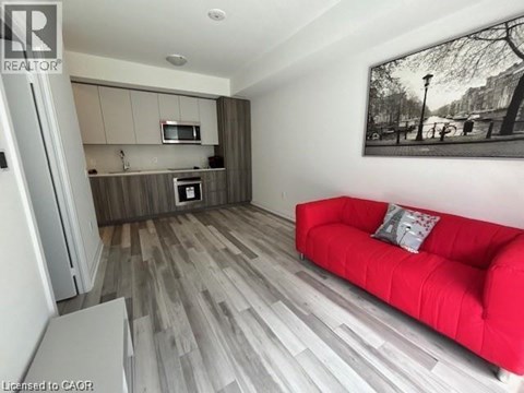 A living room with a red couch and a fridge.