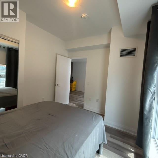 A bedroom with a bed covered in a grey sheet.