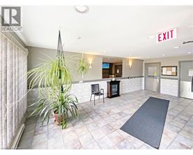 A room with a plant, a chair, and a fireplace with an exit sign above it.