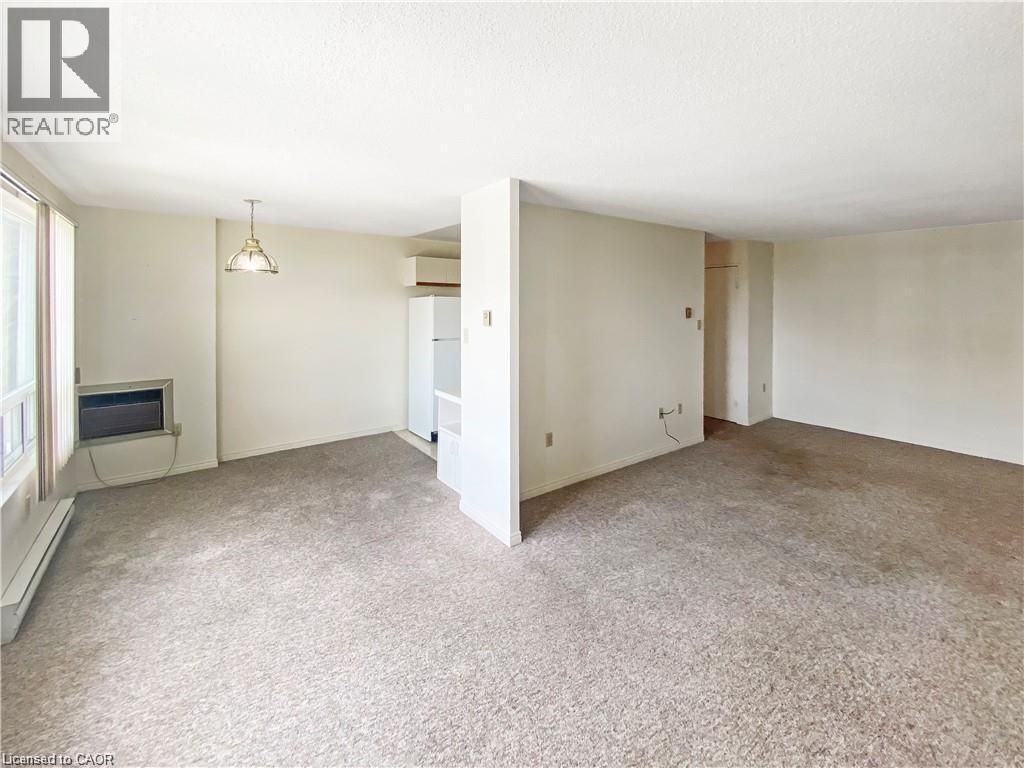 A spacious room with a carpeted floor and a television in the corner.