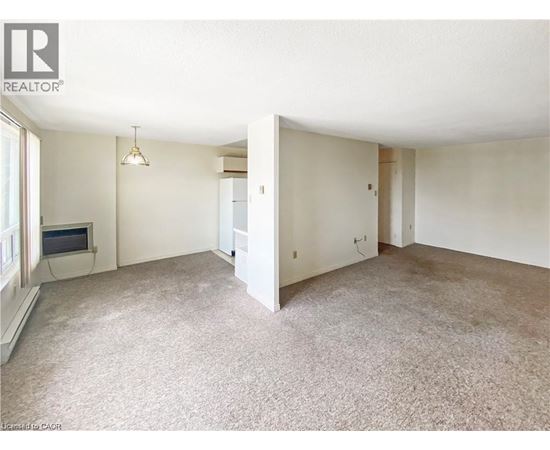 A spacious room with a carpeted floor and a television in the corner.