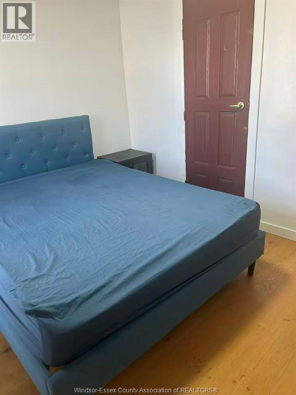 A bed with a blue cover sits in a room with a red door.