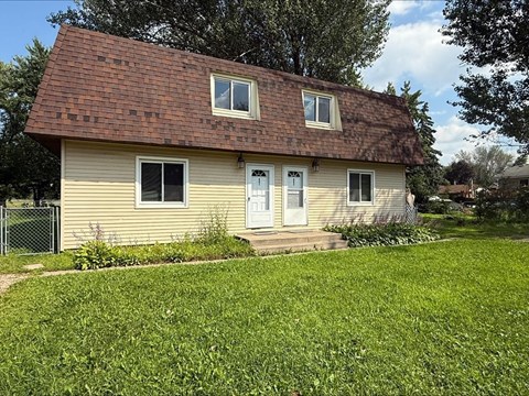 A small house with a brown roof and a white door.