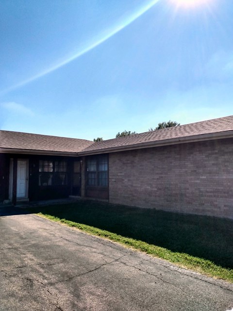 A house with a cracked driveway and a clear blue sky above.