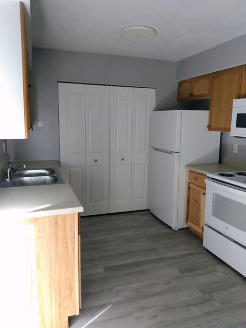 A kitchen with white appliances and wooden cabinets.