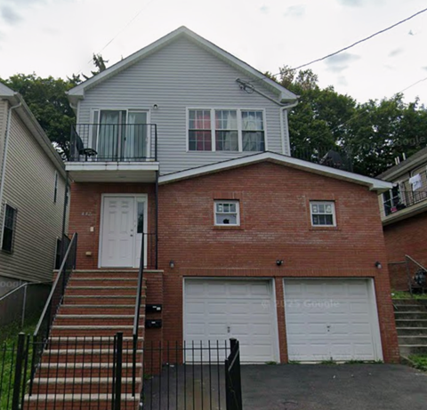 A two-story house with a garage door and a balcony.