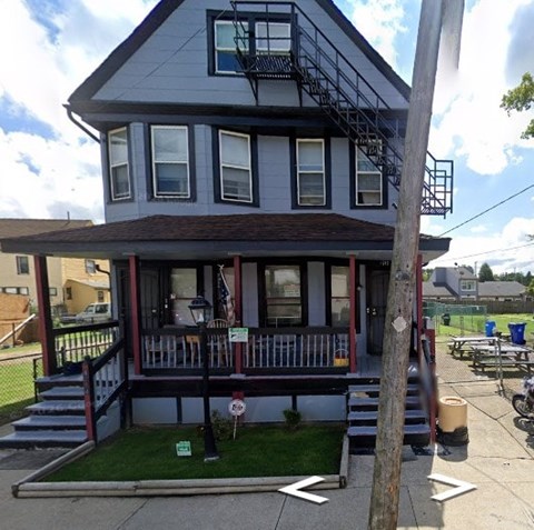 A grey house with a red and white striped awning.