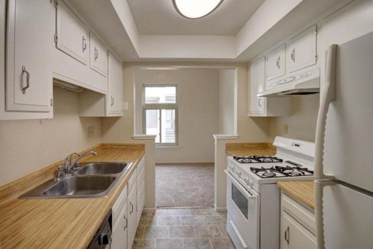 A kitchen with white cabinets and a wooden counter top.