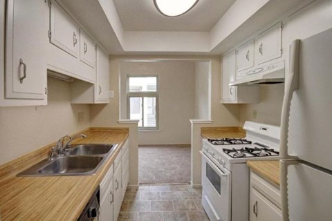 A kitchen with white cabinets and a wooden counter top.