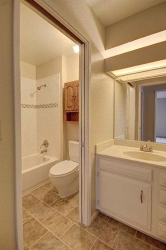 A bathroom with a toilet, sink and mirror.