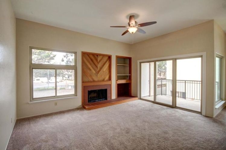A living room with a fireplace and a ceiling fan.