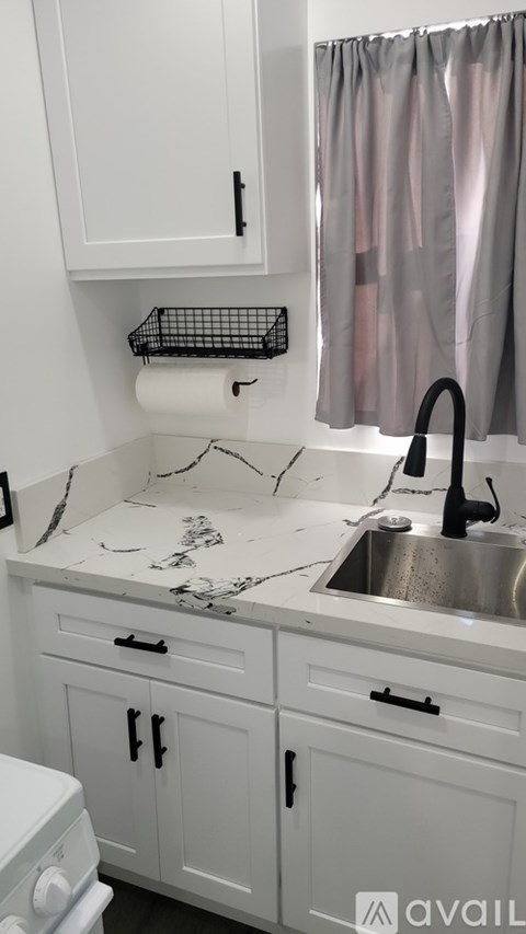 A white kitchen with a marble counter top and a sink.