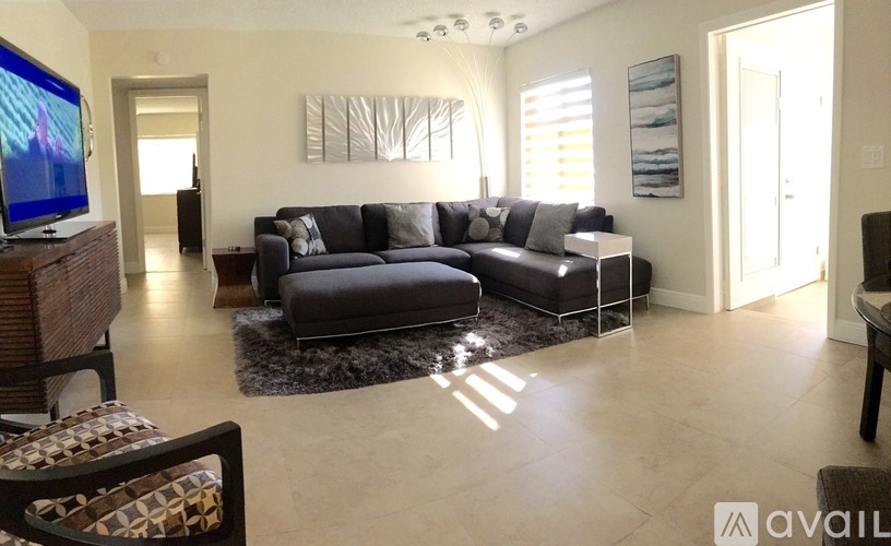 A living room with a grey couch and a television on the left side.