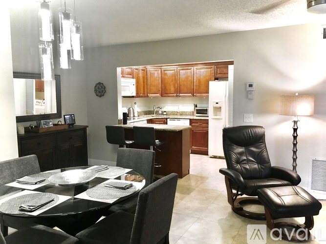 A dining room with a table set for four and a kitchen in the background.