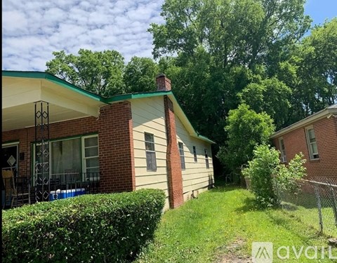 A house with a green lawn and trees in the background.
