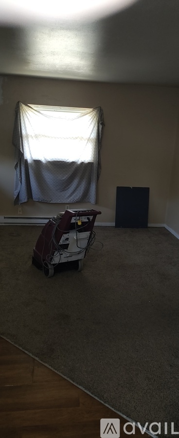 A room with a vacuum cleaner and a window with curtains.