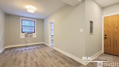 A room with a window and a wooden door is available for rent.