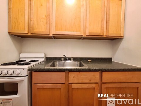 A kitchen with wooden cabinets and a white stove top oven.