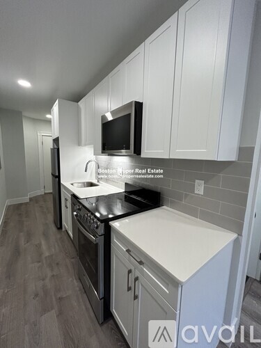 A kitchen with white cabinets and a black countertop.