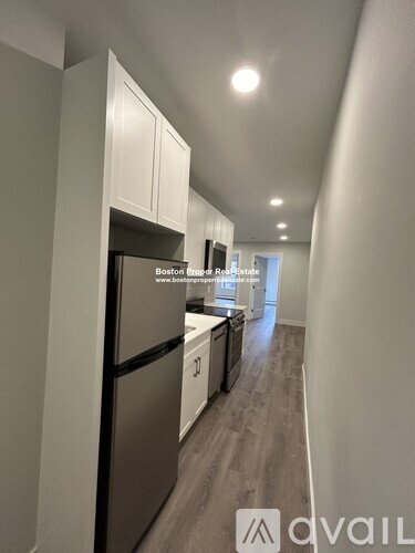 A kitchen with a refrigerator and cabinets in a narrow hallway.