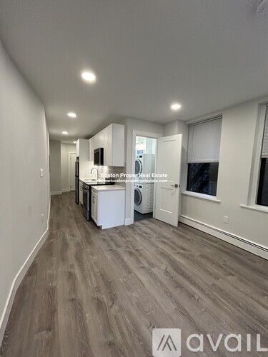 A spacious room with a kitchenette and a washer and dryer.