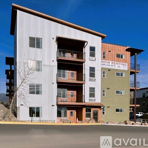 A multi-story building with a sign that says "NOW RENTING" on the side.