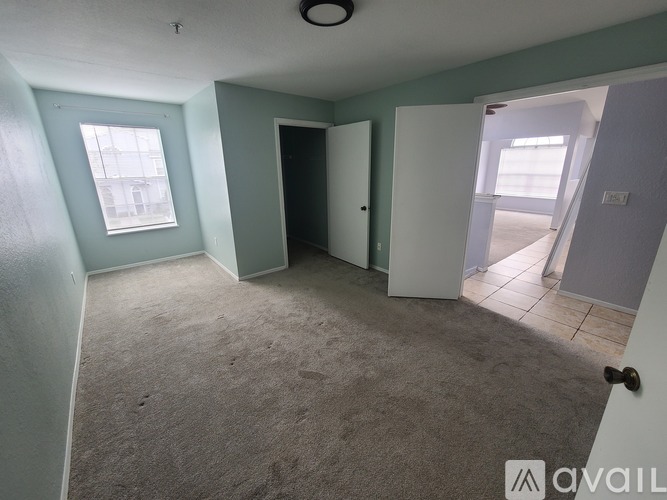 A room with a carpeted floor, a window, and a door.
