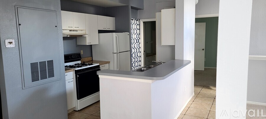 A kitchen with a white counter and a grey fridge.