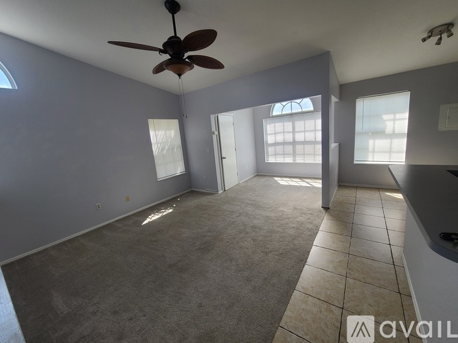 A spacious room with a ceiling fan and large windows.