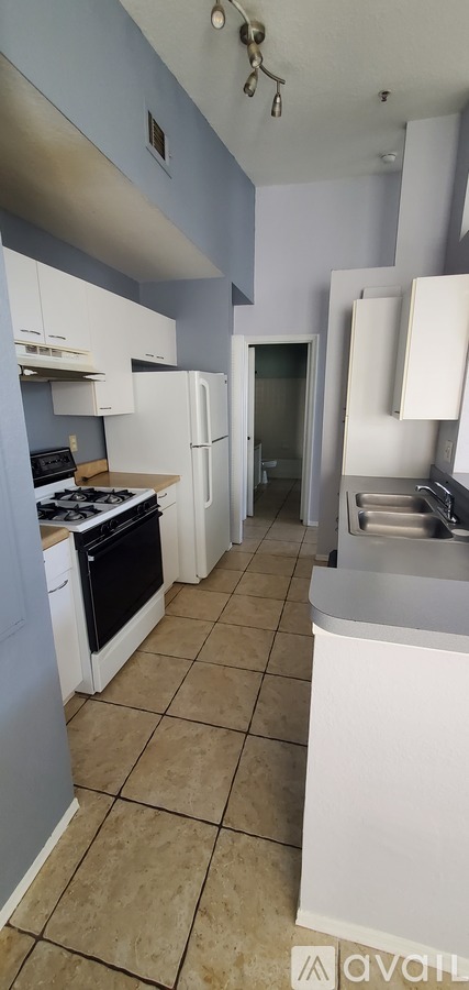 A kitchen with white appliances and a tiled floor.