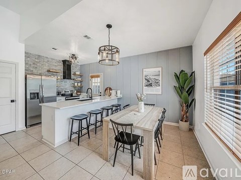 A kitchen with a table and chairs in front of a refrigerator.