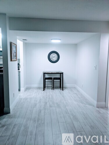 A room with a clock on the wall and a table with chairs.