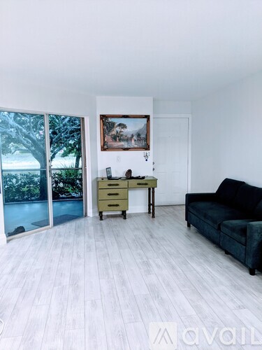 A living room with a couch, a desk, and a painting on the wall.