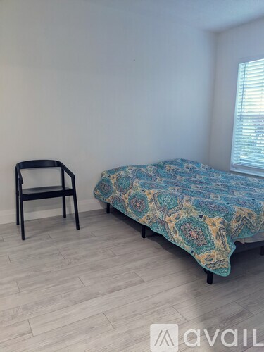 A bedroom with a bed and a chair.
