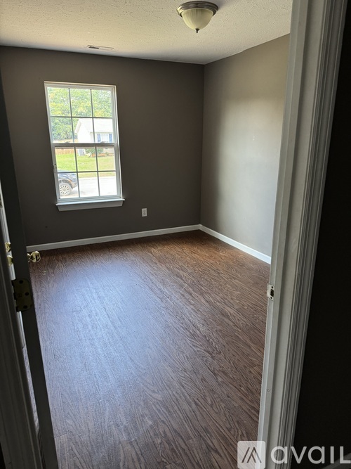 A room with a window and wooden flooring.